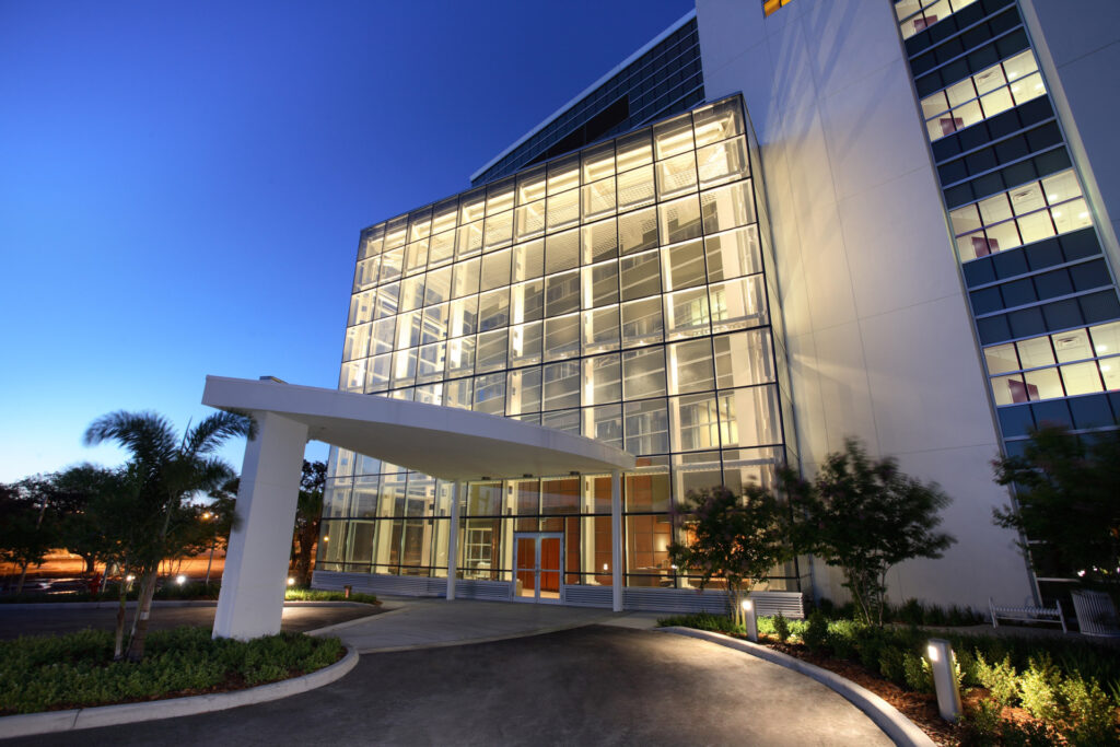 Modern glass-fronted building with a curved entrance canopy, illuminated at dusk - Lucky 5 Group Renovation.