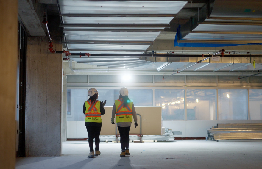 Two construction workers are walking inside a building under construction - Lucky 5 Group Renovation.