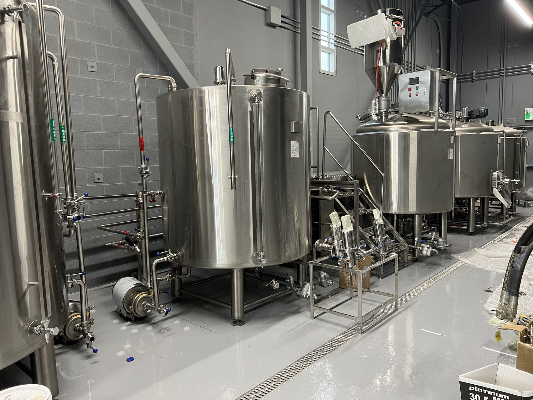 A set of industrial stainless steel tanks and equipment inside a facility - Lucky 5 Group Renovation.